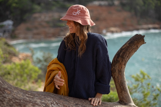 Femme assise sur une branche d'arbre avec un chapeau rose, image de légèreté et de nouveau départ